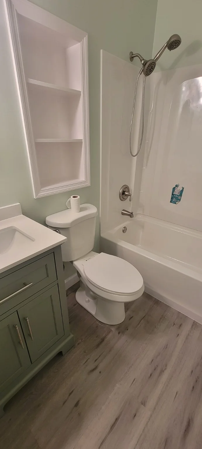 Finished bathroom with green vanity and white tub surround
